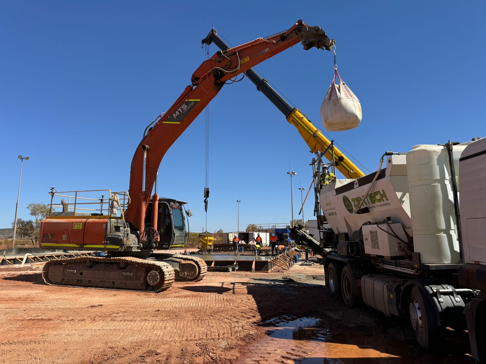 Concrete pump and crane supporting a jobsite placement