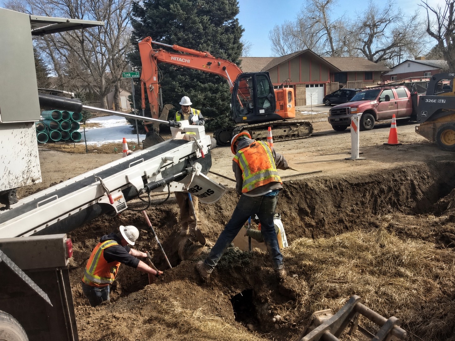Crew working around a volumetric mixer during an active trench and utility job